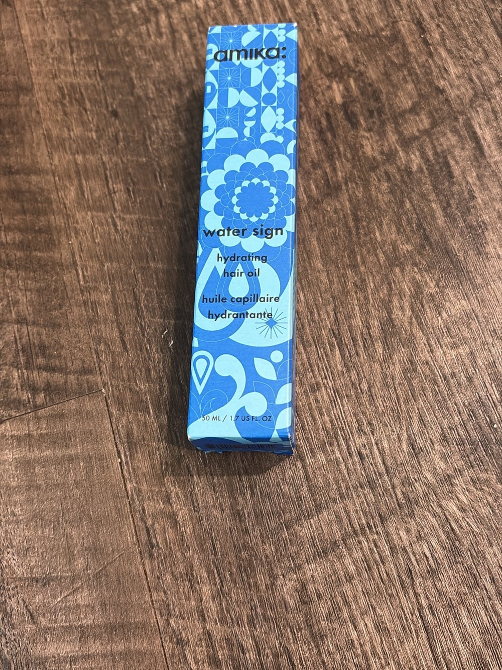 amika hydrating hair oil in bright blue patterned box